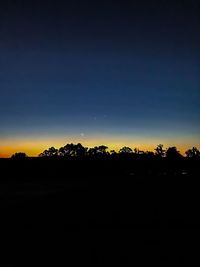 Silhouette trees on field against sky during sunset