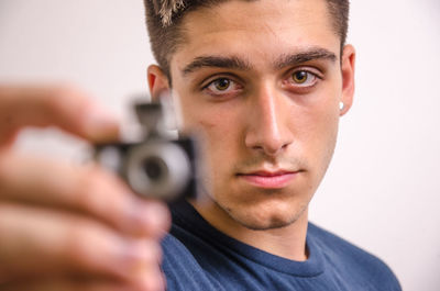 Close-up portrait of young man holding eyeglasses