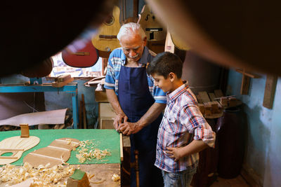 High angle view of senior man teaching instrument making to boy in workshop