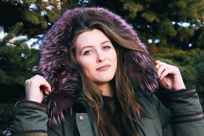 Portrait of beautiful young woman against trees