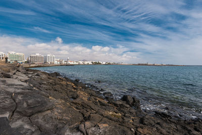 Scenic view of sea by buildings against sky