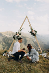 People sitting on mountain against sky