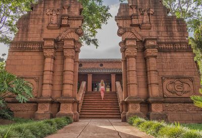 Rear view of woman climbing steps at temple