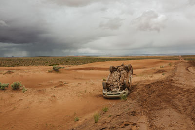 Car flipped on its top off a slippery wet dirt mud road in the desert