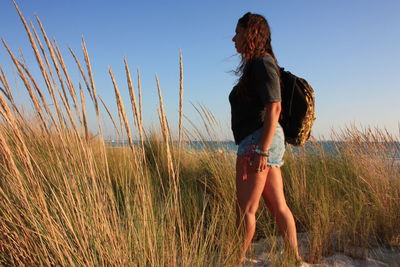 Sunset a young woman strolls among dry grass of the romantic sandy beach in rosignano sea tuscany