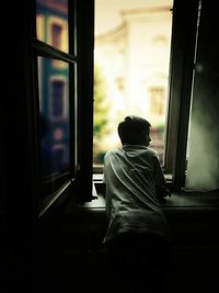 Rear view of woman looking through window