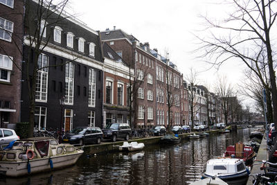 Boats moored in canal by buildings in city