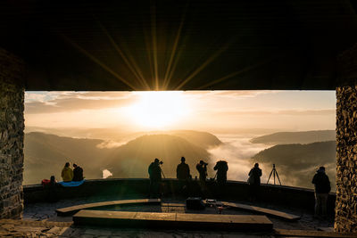 People at observation point against sky during sunset