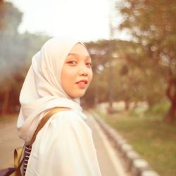 Portrait of woman wearing hijab standing on footpath in park