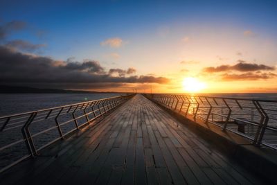 Pier over sea against sky during sunset