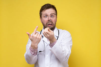 Portrait of man standing against yellow background
