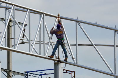 Low angle view of man working at construction site against sky