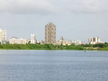 Sea by buildings against sky in city