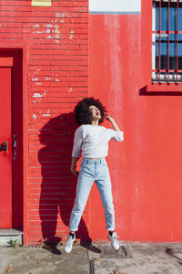 Full length of woman standing by red building