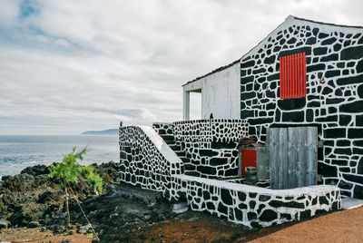 Built structure on beach by sea against sky