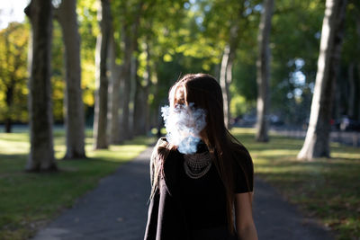 Young woman smoking while standing outdoors