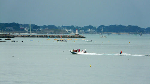 People sailing on sea against clear sky