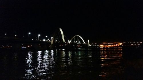 Illuminated bridge over river against sky at night