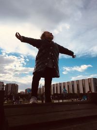 Low angle view of woman with arms outstretched against sky