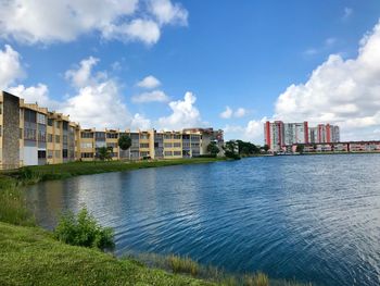 Buildings by river against sky in city