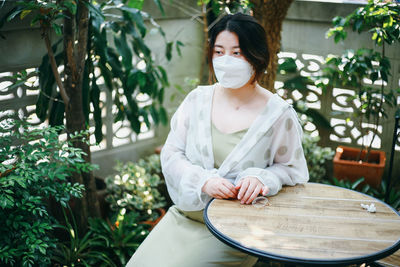 Portrait of young woman sitting against plants