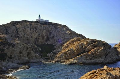 Rock formations by sea against clear sky