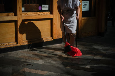 View of lady outside with dustpan and brush 