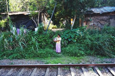 Rear view of woman standing by railroad tracks