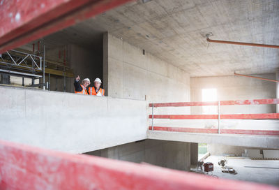 Two men wearing safety vests talking in building under construction