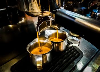 Close-up of coffee pouring from espresso maker in cafe