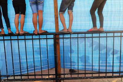 Low section of people standing by tarpaulin on railing