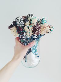 Close-up of hand holding ice cream over white background