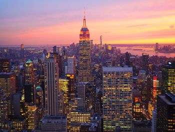 Illuminated buildings in city against sky during sunset