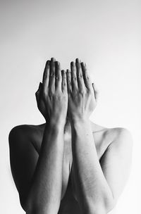 Shirtless woman covering face with hands while standing against white background