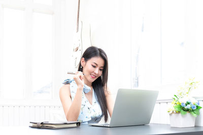 Young woman using mobile phone while sitting on table