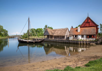 Building by river against clear blue sky