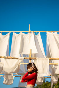 Rear view of clothes drying on clothesline against clear blue sky