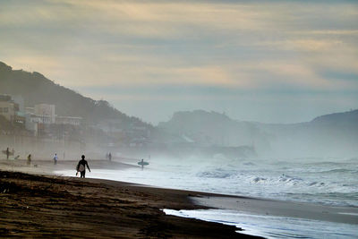 People walking on beach against sky