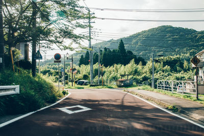 Road by trees against sky