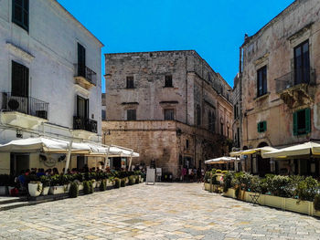 Street amidst buildings against blue sky