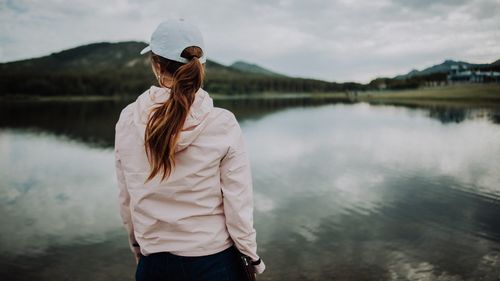 Rear view of woman standing by lake