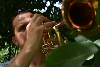 Close-up of man playing trumpet by plants