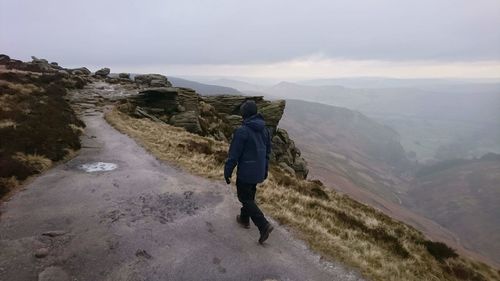 Rear view of man on mountain against sky