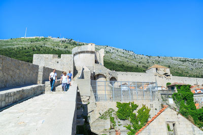 People standing outside building against blue sky