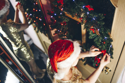 High angle view of woman decorating wreath at home during christmas