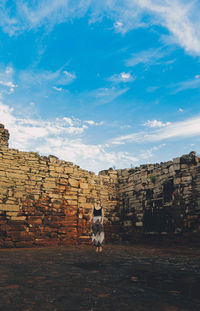 Full length of woman standing at old ruins against sky