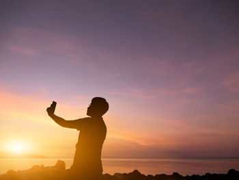 Silhouette man taking selfie at beach during sunset