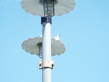Low angle view of telephone pole against clear blue sky