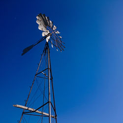 Low angle view of wind turbine against blue sky