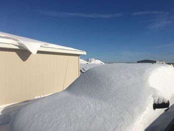 Built structure on snow covered landscape against blue sky